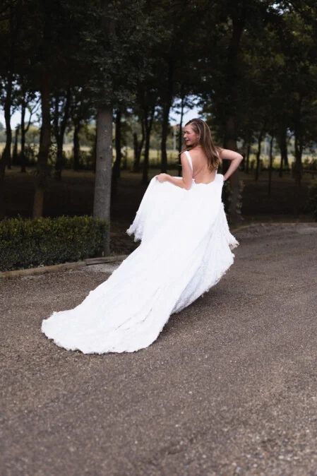Bride walking with her wedding dress at Tenuta Torciano in San Gimignano, Tuscany – smiling and looking back, photographed by wedding photographer Vanni Frassoni