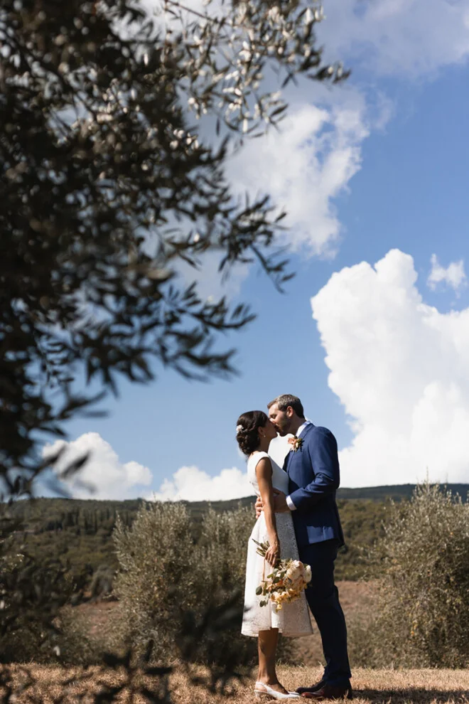 Bride and groom sharing a kiss among olive trees in the countryside of San Gimignano, Tuscany.
