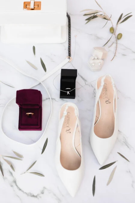 Flat lay of wedding details in Tuscany: white shoes, rings, jewelry and bride accessories, photographed by Vanni Frassoni