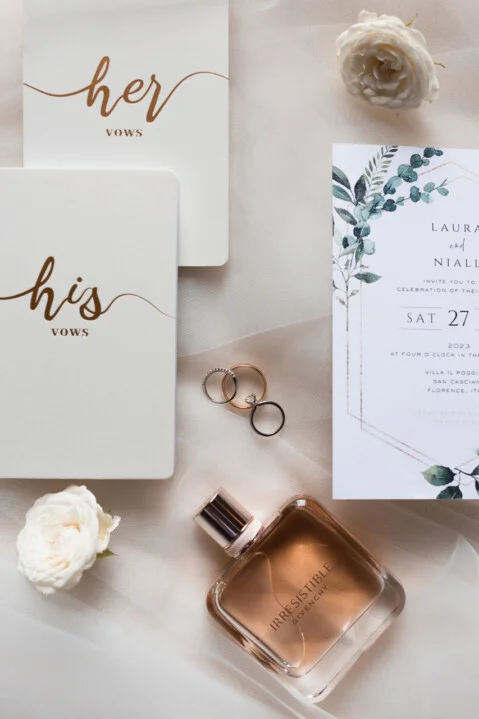 Elegant flat lay wedding details in Tuscany – bridal invitations, rings, perfume and flowers photographed by Vanni Frassoni
