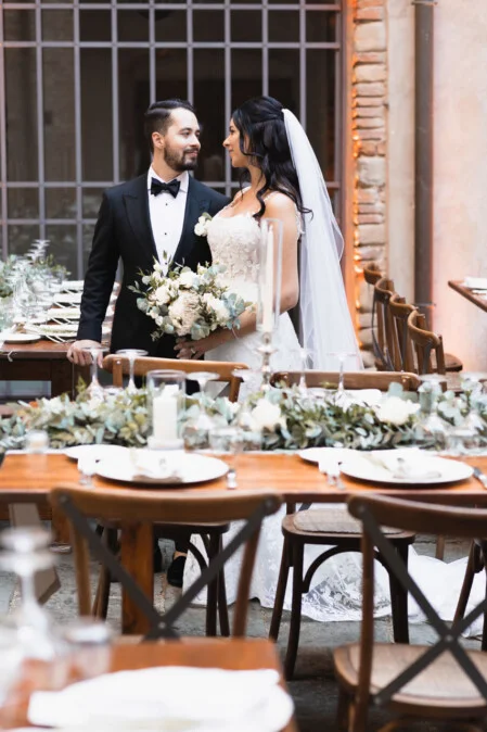 Sposi al ricevimento di matrimonio in Toscana, accanto a un tavolo decorato con candele e fiori, fotografati da Vanni Frassoni.